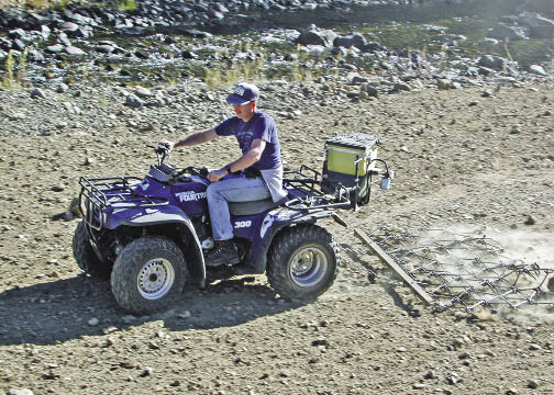 Figure 10.91 - Seed sowing and mixing equipment can be attached to most types of ground based equipment, including all-terrain vehicles. A seed spreader attached to the back of an all-terrain vehicle broadcasts seeds on the soil surface and a chain harrow mixes seeds into the soil.