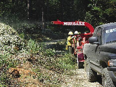 Figure 5.72 - Slash material can be chipped on site to reduce fire hazards and increase line of sight. In this photograph, brush and trees on cut slopes are cut, chipped, and blown back on the slopes as mulch.